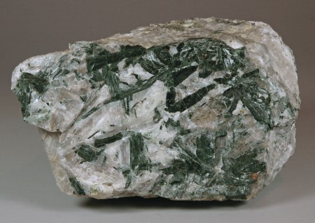 Long-bladed crystals of dark green actinolite in a matrix of coarse-grained, pale gray calcite, tiny grains of franklinite 