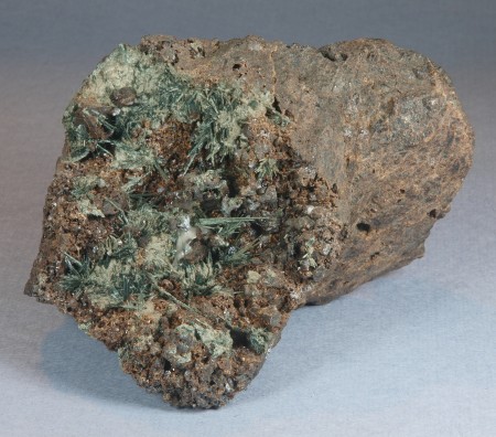 Radiating sprays of dark green, acicular actinolite crystals 0.5-2 cm long on brown andradite crystals