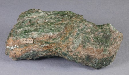 Contorted mass of green, bladed actinolite crystals in a matrix of brown, iron-stained calcite