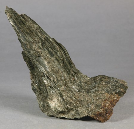 Splintery mass of dark green actinolite in tightly intergrown, contorted fibers, associated with dark brown andradite 