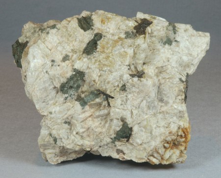 Black, tabular 1-2 cm long grains of allanite embedded in coarse-grained feldspar with minor quartz.