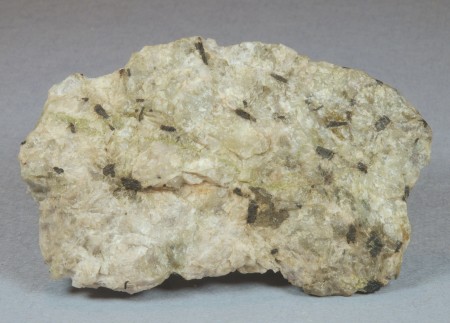 Black, tabular 4-7 mm long grains of allanite embedded in coarse-grained feldspar
