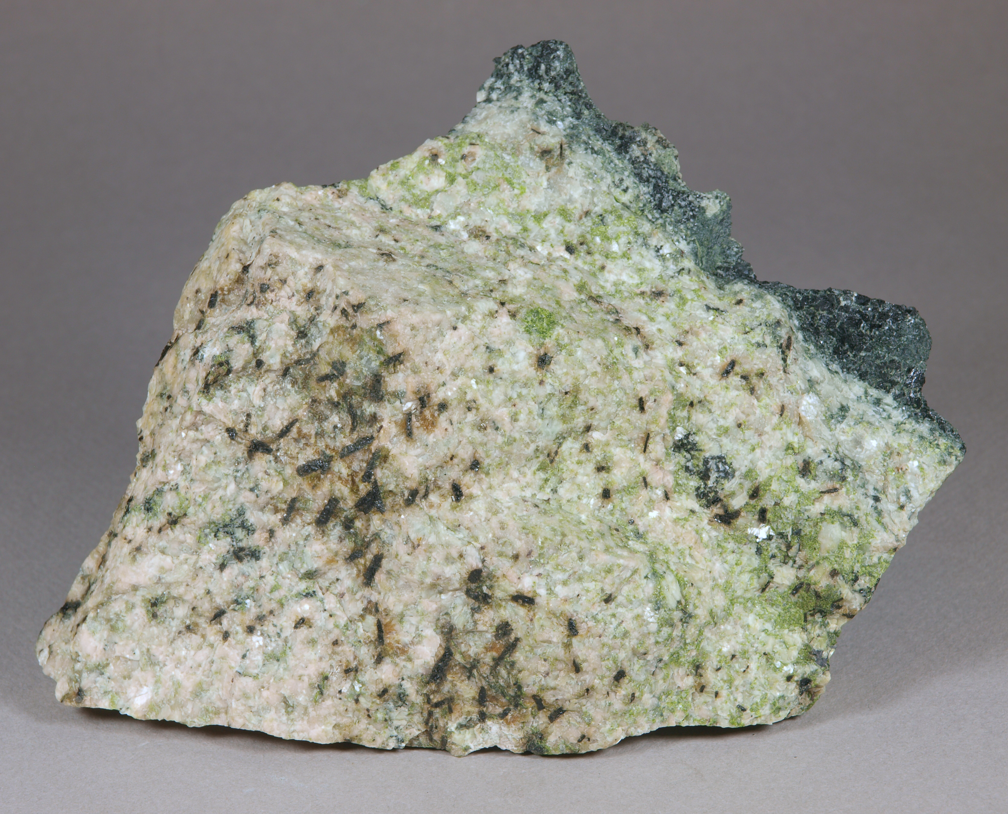 Glassy, nearly black allanite, most 4-7 mm in length on ivory-colored feldspar partly altered to green epidote