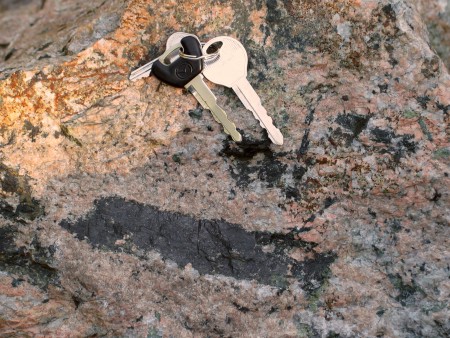 Large allanite crystal, slightly more than 15 cm long, embedded in microcline-quartz pegmatite rock