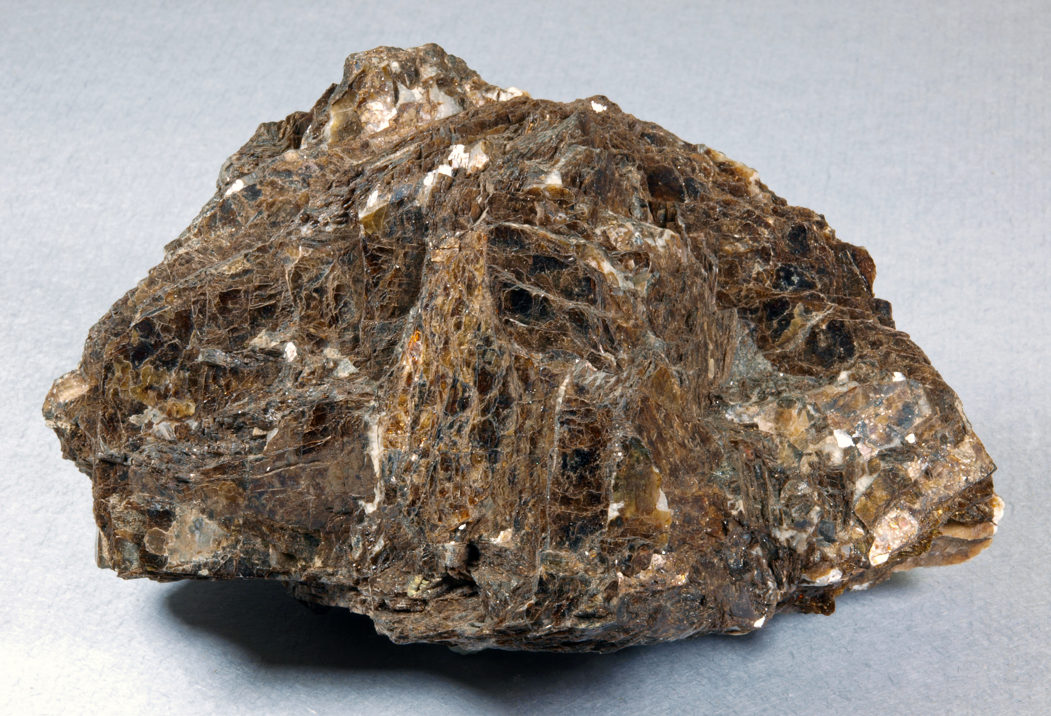 Dark brown, lustrous, coarse-grained mass of bannisterite with minor white calcite