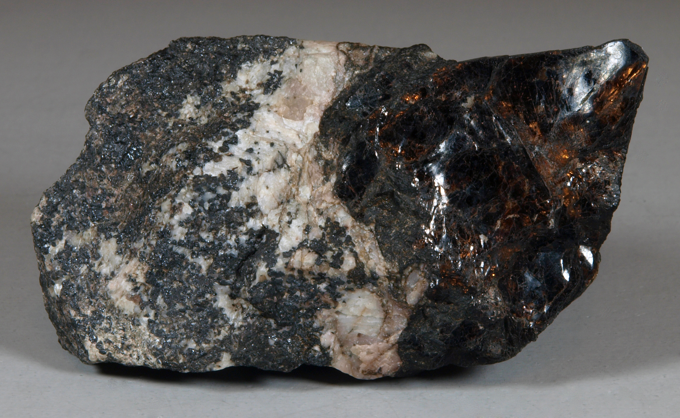 A cleavage mass of lustrous, dark brown bannisterite, white calcite, fine-grained franklinite-willemite ore.  