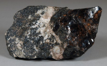 A cleavage mass of lustrous, dark brown bannisterite, white calcite, fine-grained franklinite-willemite ore.  