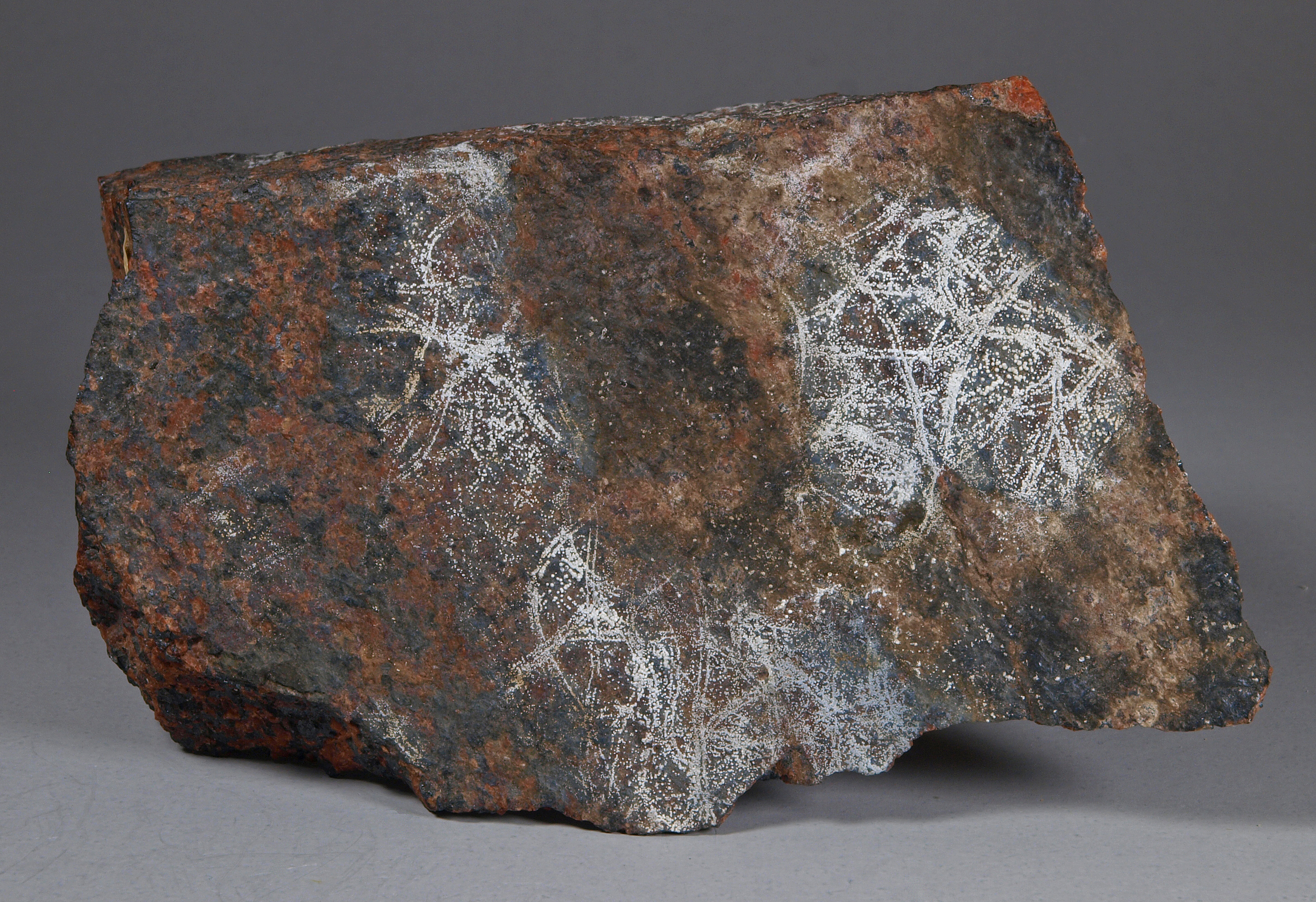 Tiny hemispherules of white dypingite on a fracture surface, brick-red willemite and black franklinite