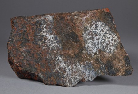 Tiny hemispherules of white dypingite on a fracture surface, brick-red willemite and black franklinite