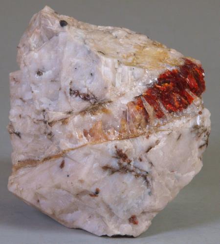 Elongate, orange-tan, translucent crystals of gerstmannite with dark red zincite vein, coarse-grained calcite marble