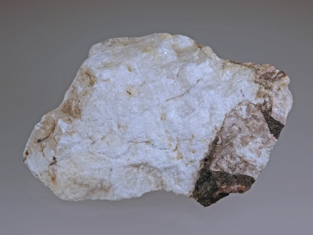 Massive, fine-grained, translucent gypsum with clasts of coarse-grained calcite and local coatings of black pyrochroite