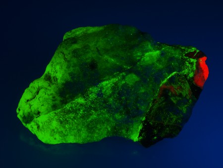 Massive, fine-grained, translucent gypsum with clasts of coarse-grained calcite and local coatings of black pyrochroite under shortwave UV Light