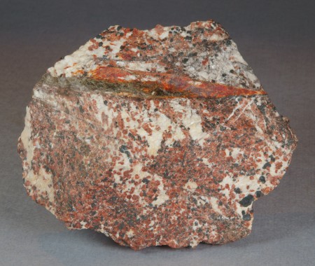 Dark olive green to (locally) dark brown magnussonite and orange-red zincite