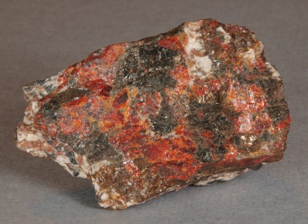 Assemblage of glassy, dark brown magnussonite with bright orange-red zincite