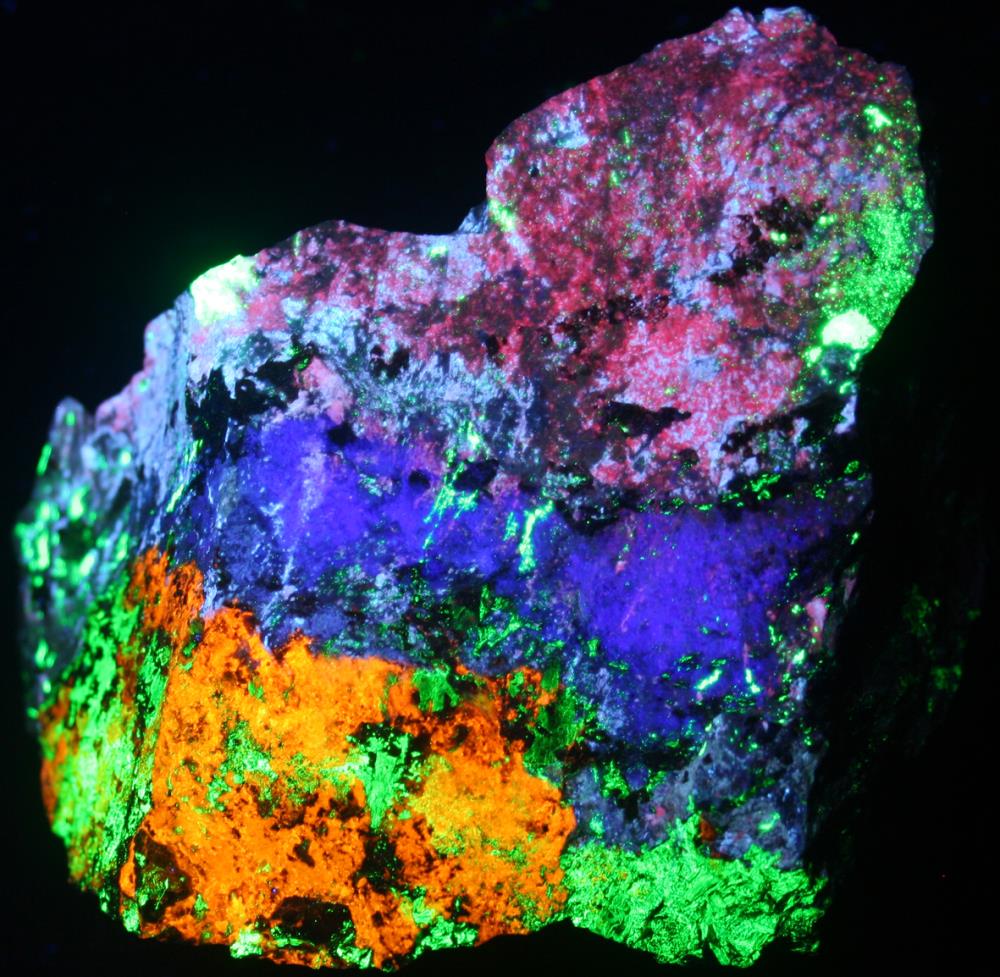 Fluorescent margarosanite, feldspar, hardystonite, clinohedrite, willemite under shortwave UV light.