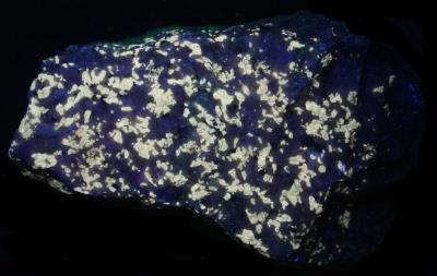 Fluoborite grains in calcite / marble, with graphite and pyrite, Sterling Hill Mine under shortwave UV Light