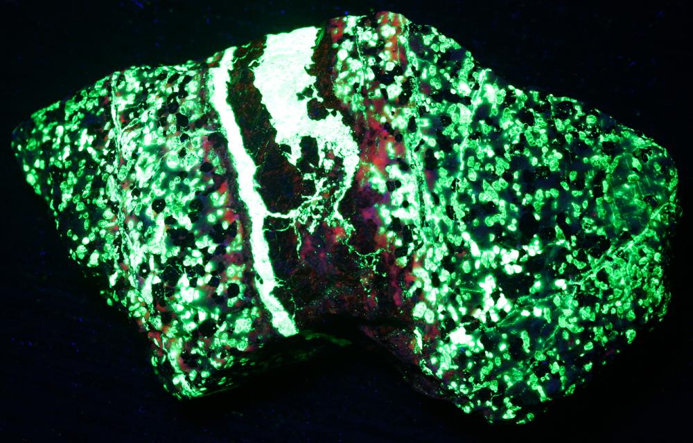 Sphalerite vein in willemite, calcite, franklinite ore from Sterling Hill, NJ. under shortwave UV Light